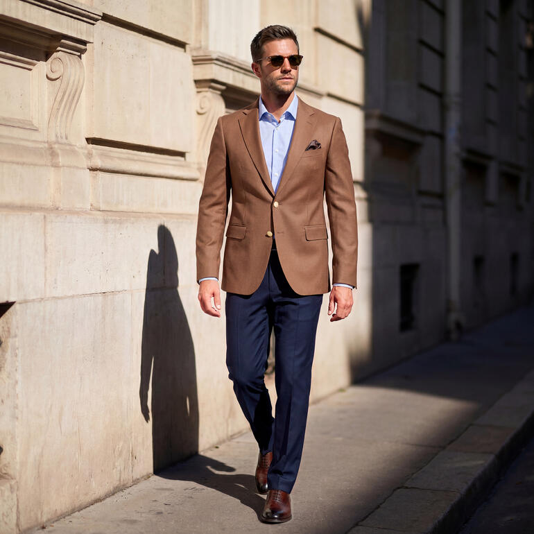 Homme en blazer Hopsack Carl Gross marchant dans une rue de la ville.