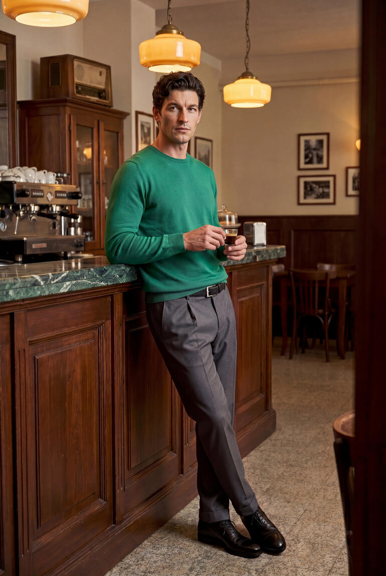 Homme en pull en soie Junghans 1954 appuyé au bar d'un café.