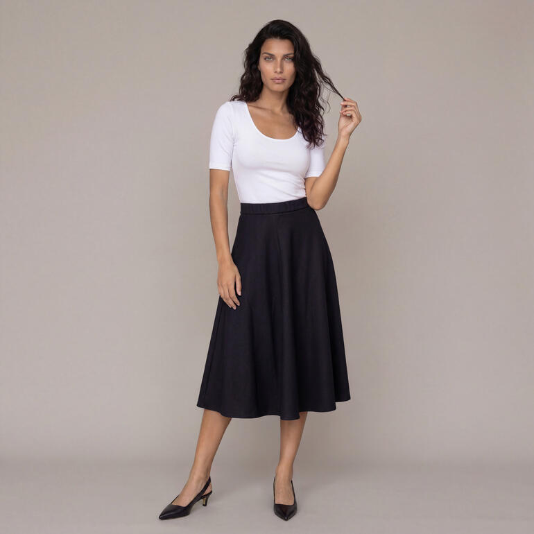 Femme portant une jupe en laine noire avec un haut blanc.
