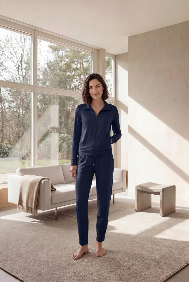Femme debout dans un ensemble modal gris devant une grande fenêtre.