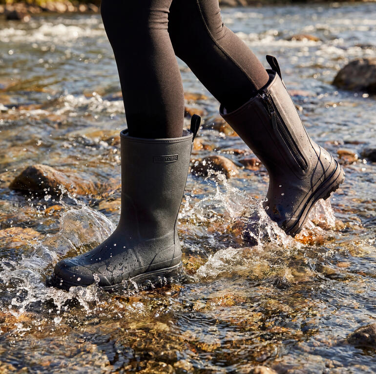 Bottes en caoutchouc noires aux pieds d'une personne dans l'eau
