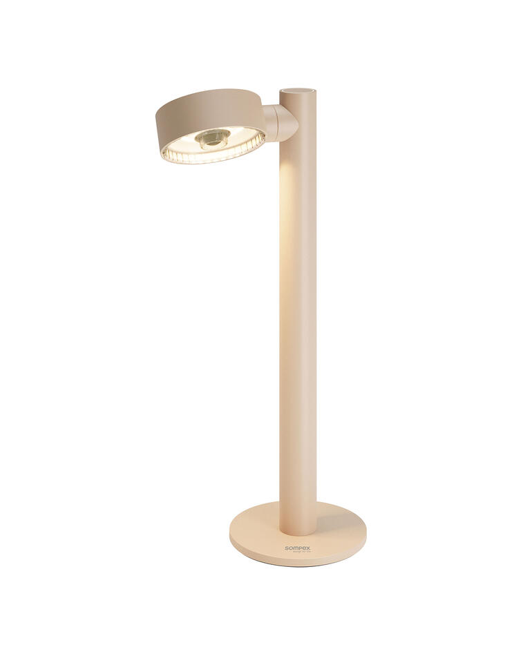 Lampe de table à batterie en couleur sable, posée sur une table.