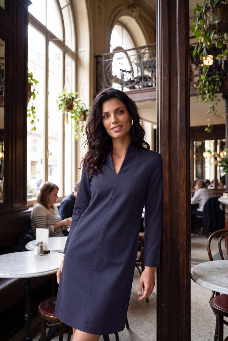Femme dans une petite robe bleue avec col bateau dans un café.