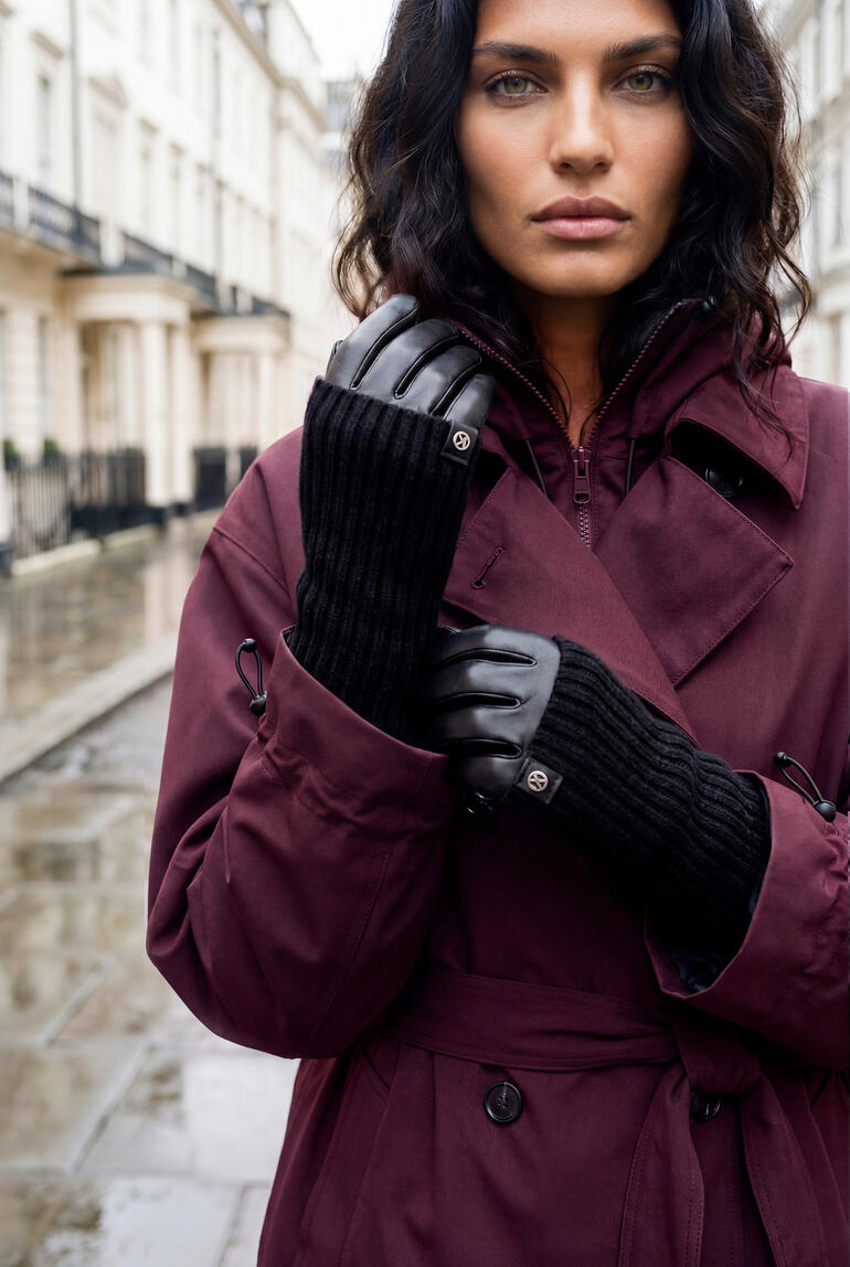 Femme debout dans une rue pluvieuse portant un trench-coat prune.