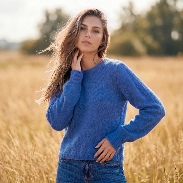 Femme portant un pull en alpaga-mohair bleu dans un champ.