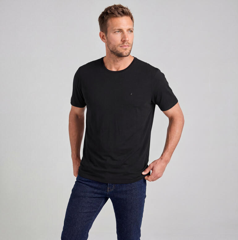 Homme en t-shirt en merino noir devant un fond neutre.