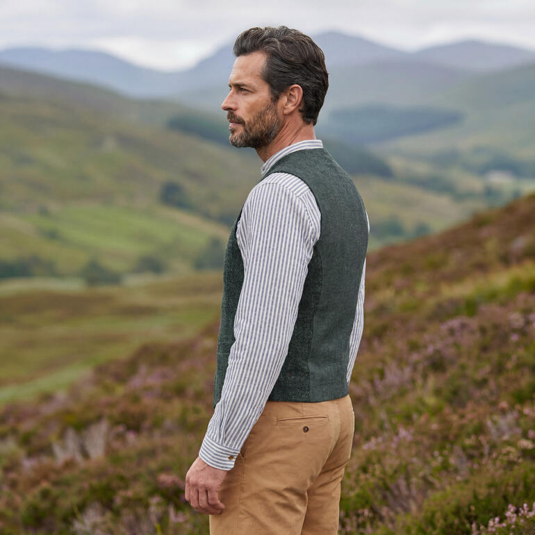 Gilet en tweed anthracite porté par un homme dans la nature.