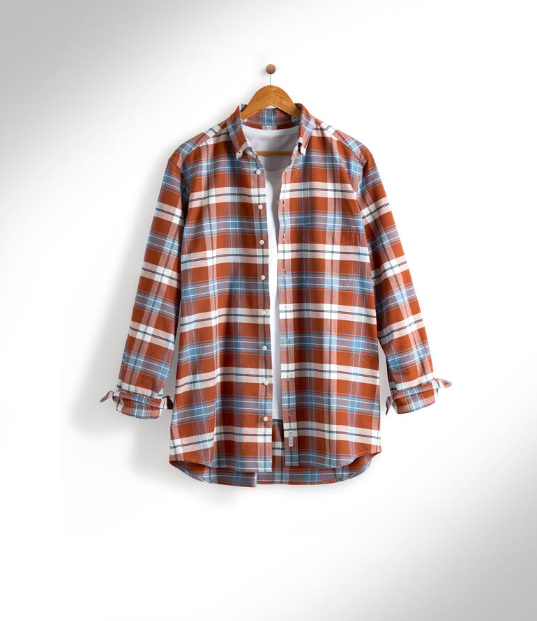 Chemise à carreaux dans des couleurs chaudes accrochée à un cintre en bois.