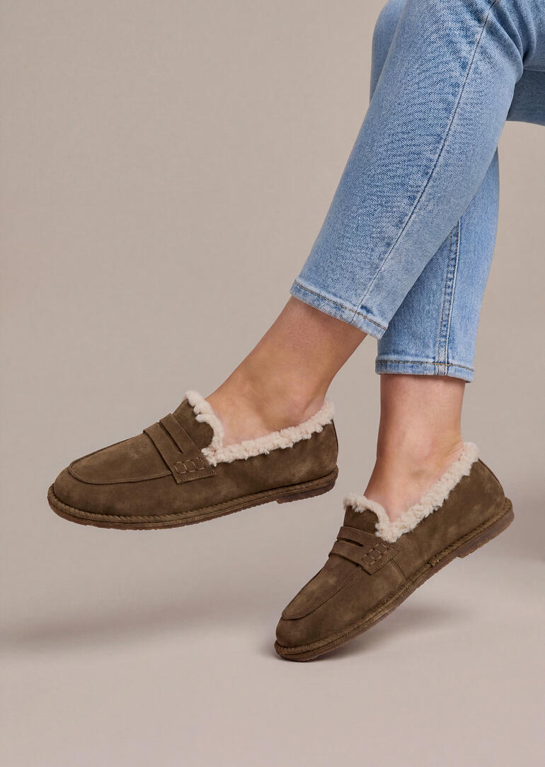 Pieds dans des loafers en peau de mouton marron, vue de côté.