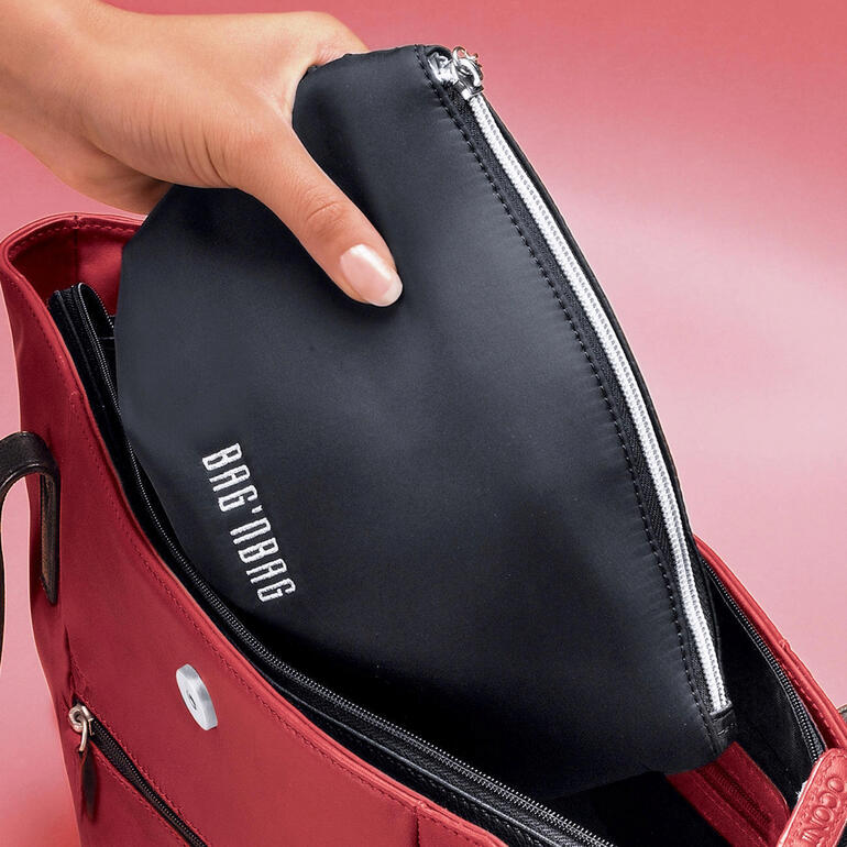 Main mettant un sac noir dans un sac rouge.